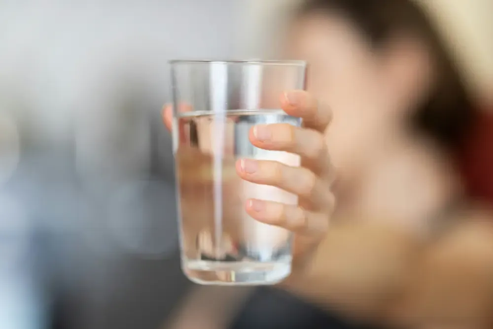 A glass of water being held up by a woman