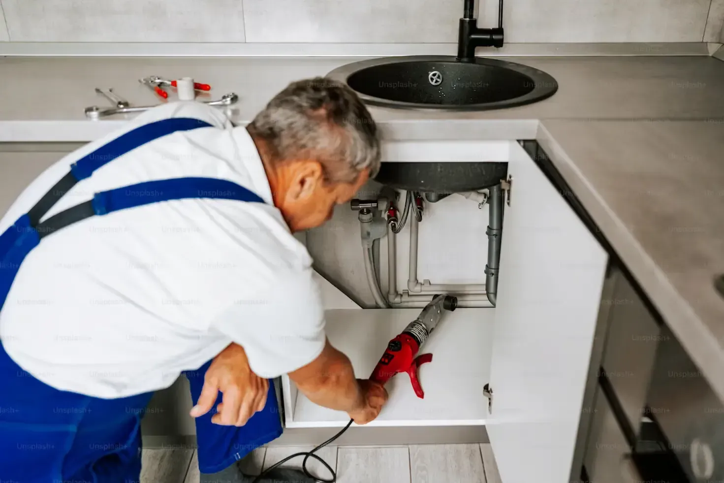 Man servicing undersink plumbing