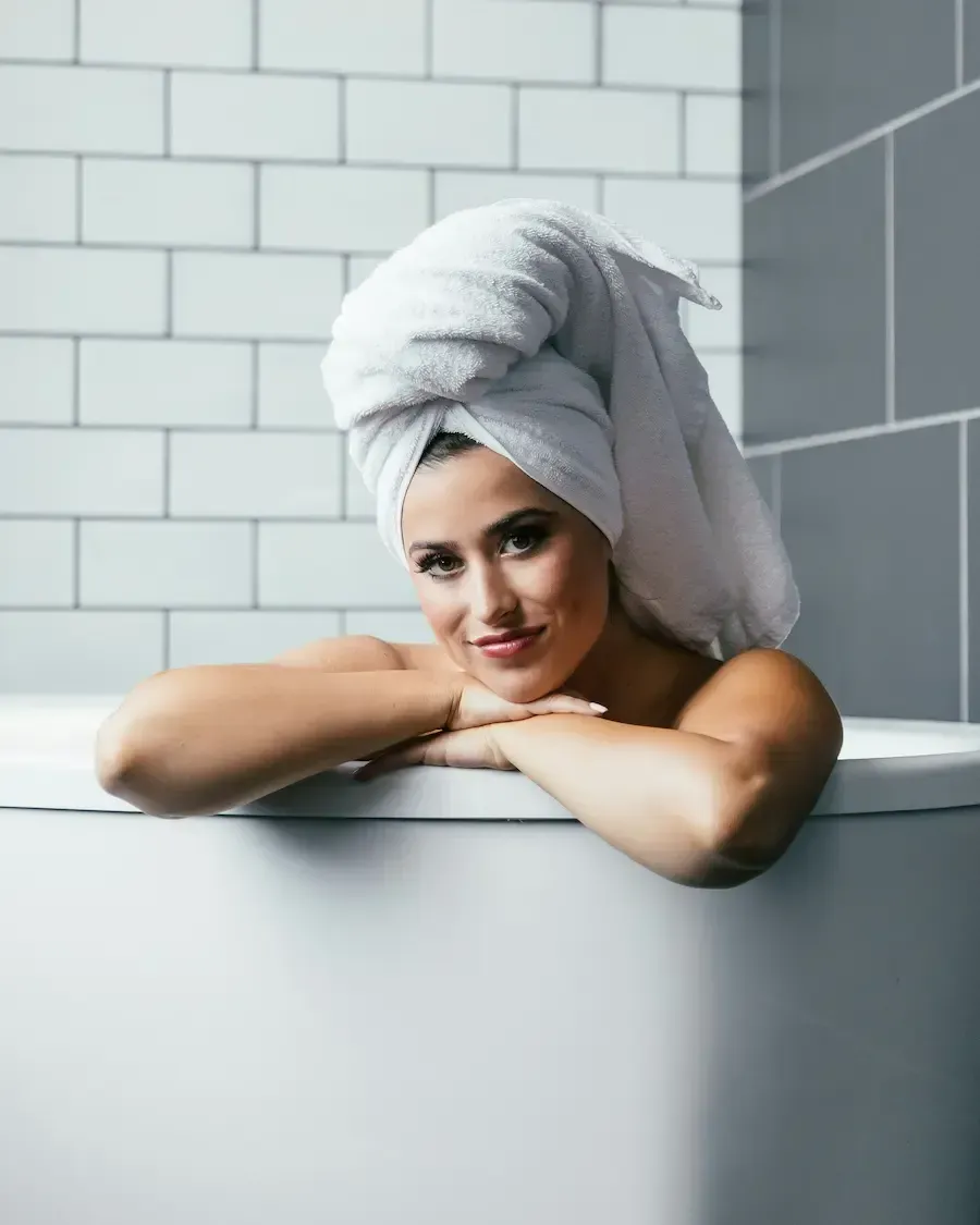 A woman in the bath with a towel over her hair